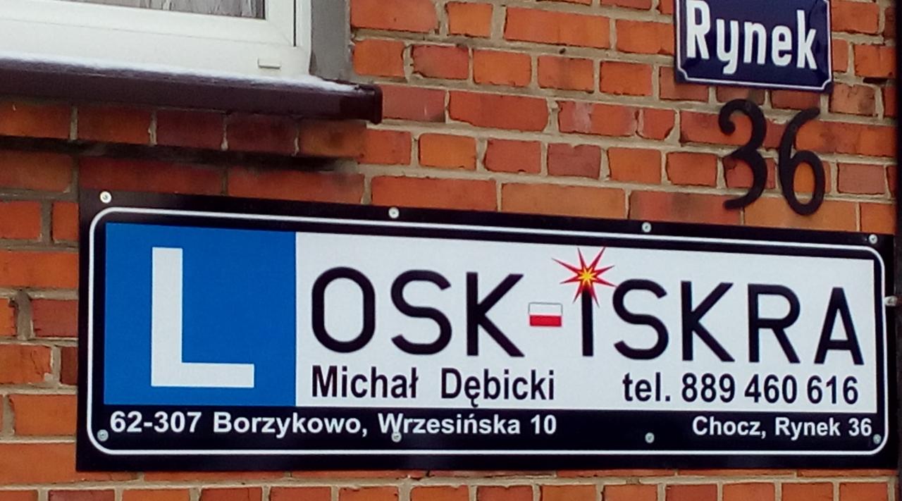 Szyld szkoły jazdy OSK-ISKRA Michała Dębickiego, z adresem i numerem telefonu, przymocowany do ceglanej ściany budynku obok tabliczki z nazwą ulicy Rynek 36.