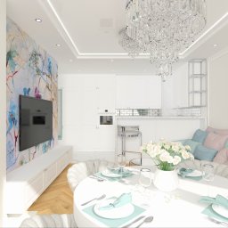 IMO studio - Jasne wnętrze z okrągłym stołem, kwiatami i kryształowym żyrandolem. Ściana z abstrakcyjnym wzorem, telewizor i białe meble. Pastelowe akcenty kolorystyczne.