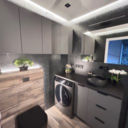 Fachowiec - Nowoczesna łazienka w szarościach z akcentami drewna: umywalka nablatowa, toaleta w zabudowie, pralka i oświetlenie LED. Minimalistyczny design z roślinnymi dekoracjami.