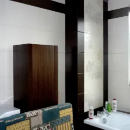 Wykończona łazienka z białymi i ciemnobrązowymi płytkami, dekoracyjnym pasem z motywem ornamentu, szafką z ciemnego drewna oraz wanną z kosmetykami, widok częściowo zasłonięty przez krzesło...