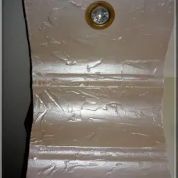 Fragment dekoracyjnej ściany z oświetleniem punktowym w kolorze beżowym, z widoczną fakturą i zdobieniami sztukateryjnymi.