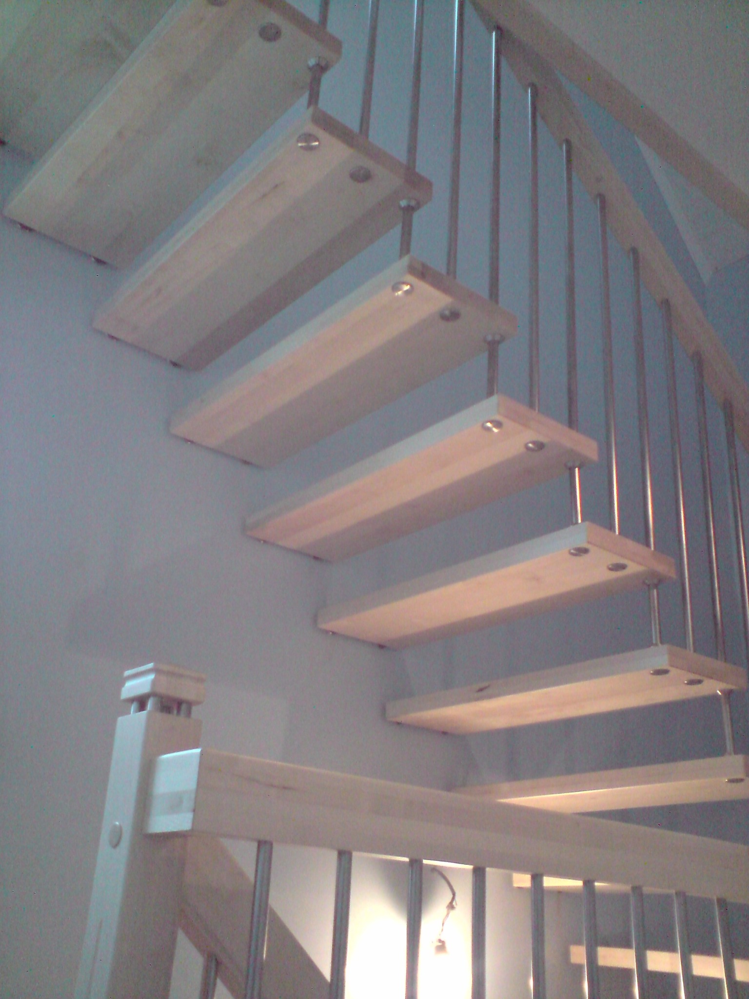 Schody drewniane z metalowymi balustradami, stopnie mocowane do ściany, widok z dołu.