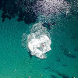 API Studio - Widok z drona na osobę uprawiającą flyboard na turkusowej wodzie, z fontanną wody i łodzią w pobliżu.