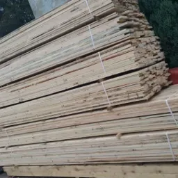 Stos tarcicy budowlanej na paletach, zabezpieczony taśmą, z widocznym logo firmy KARBUD w tle.