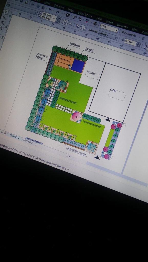 Rzut z góry na projekt ogrodu z zaznaczonym tarasem, domem, huśtawką, jacuzzi, trawnikiem i drewnianą ścianą, widoczny na ekranie komputera z otwartym programem graficznym.