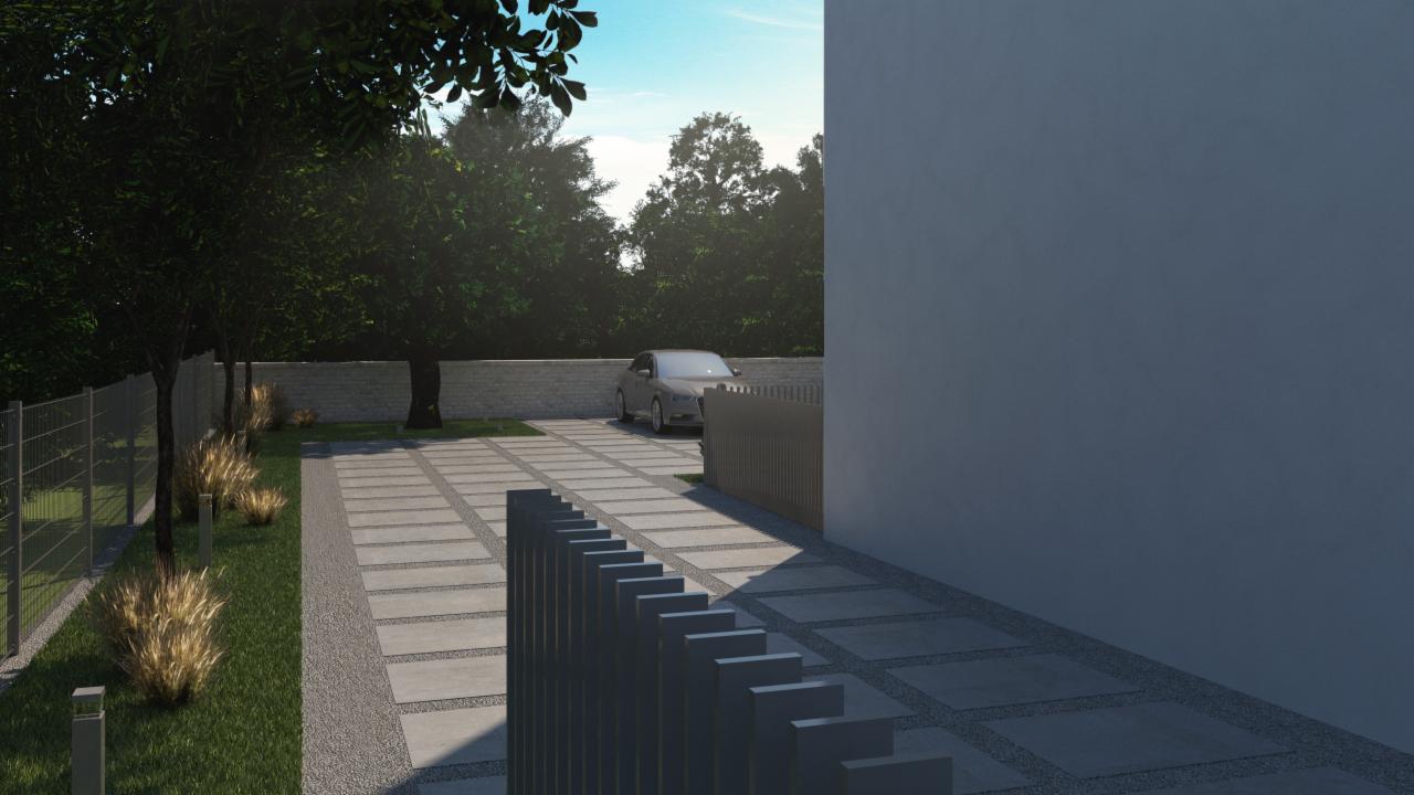 Nowoczesny podjazd wyłożony betonowymi płytami z szarym żwirem, ogrodzony metalowym płotem, z widocznym samochodem w tle i elementami zieleni.