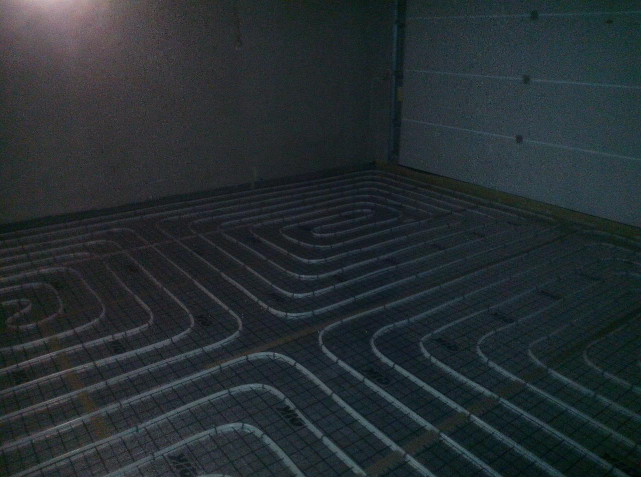 Instalacja ogrzewania podłogowego z rur w kształcie meandru, widok z góry na siatkę z rurami w surowym wnętrzu, przygotowanie do wylewki.