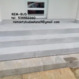 Wykończone, jasnoszare płytki na schodach wejściowych do domu z białymi kolumnami, widoczne logo firmy 'REM-BUD' oraz dane kontaktowe.