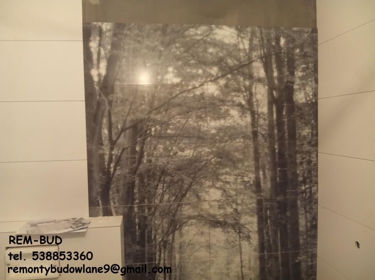 Fototapeta z motywem leśnym, ułożona z płytek w łazience w Białogardzie, z widocznym logo firmy remontowej REM-BUD i danymi kontaktowymi.