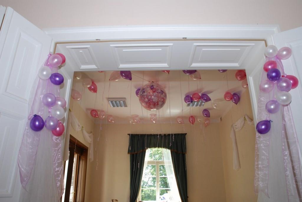 Dekoracja sali balonami w odcieniach różu i fioletu, balony przyczepione do sufitu i ramy drzwi, dodatkowo tiulowa dekoracja na drzwiach.