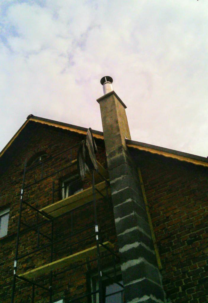 Mur z cegły z rusztowaniem i kominem z elementami szalunkowymi, widok z dołu.