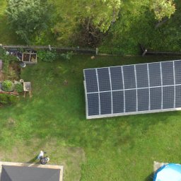 EL-MONTER Instalacje i Pomiary Sp. z o.o. - Widok z góry na panele słoneczne w ogrodzie, obok drewniany płot, mały basen i zadaszenie