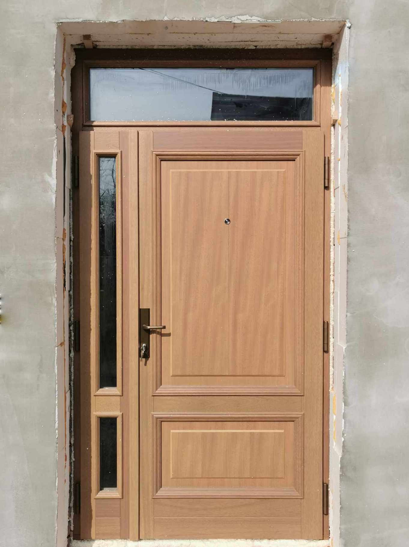 Zewnętrzne drzwi wejściowe z drewnianym wykończeniem i przeszkleniem nad drzwiami oraz po lewej stronie, zamontowane w surowym otworze ściennym.