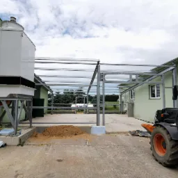 Montaż szkieletu stalowego z widocznym agregatem chłodniczym, w tle zbiornik gazu i budynek gospodarczy.