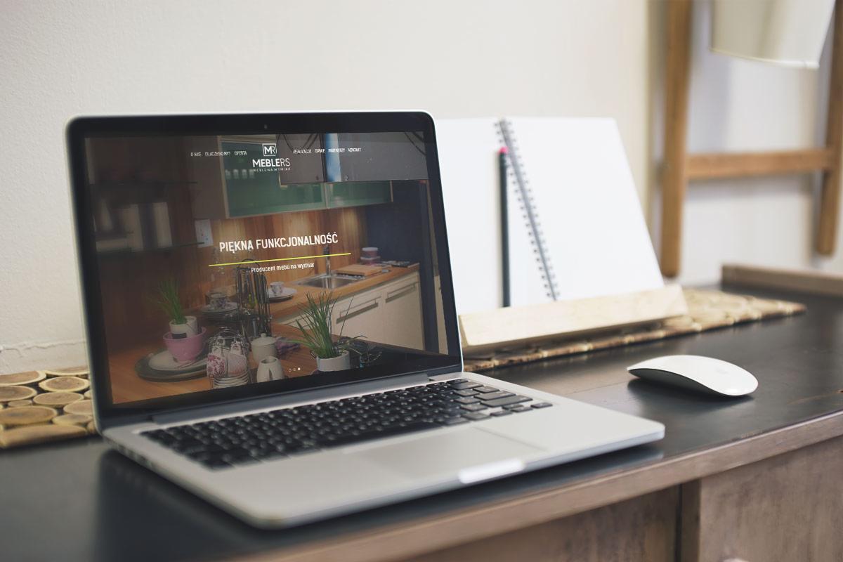 Laptop wyświetlający stronę internetową firmy meblarskiej z hasłem 'Piękna Funkcjonalność', obok notatnik i myszka.
