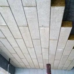 Płyty izolacyjne z wełny mineralnej układane na poddaszu, widok od dołu, surowy betonowy strop w tle.