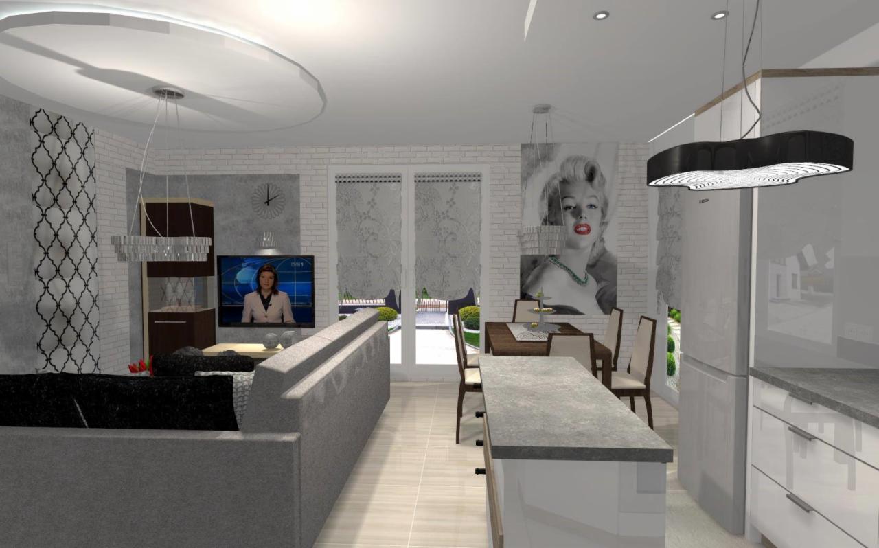 Wizualizacja przestronnego salonu z aneksem kuchennym w Wieluniu, z szarą sofą, stołem jadalnym i portretem Marilyn Monroe na ścianie z cegły.