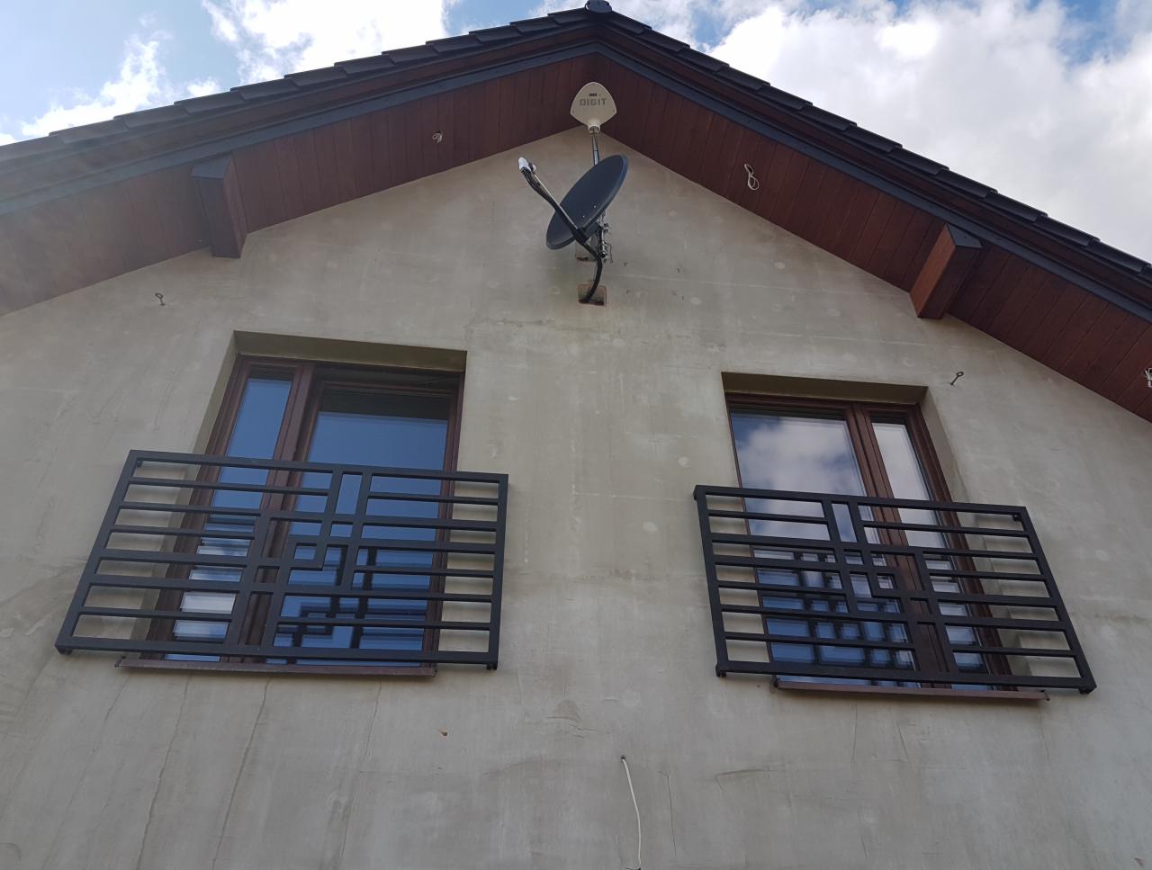 Zamontowane, metalowe balustrady balkonowe o nowoczesnym wzorze na elewacji domu jednorodzinnego z anteną satelitarną.