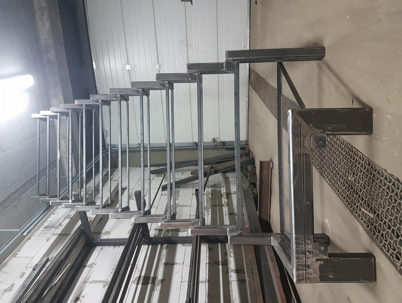 Konstrukcja stalowa schodów w trakcie tworzenia, widoczne spawy i elementy metalowe, surowe wykończenie.