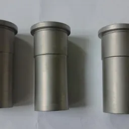 Trzy metalowe tuleje o różnych wysokościach, z widocznymi śladami obróbki, ustawione równolegle na jasnym tle. Detal wykonany z precyzją.