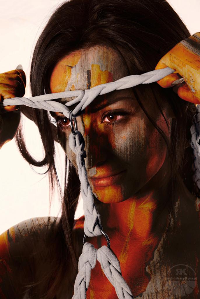 Portret kobiety z artystycznym efektem malarskim na twarzy i ciele, stylizacja z użyciem plecionego sznura z metalowymi kółkami.