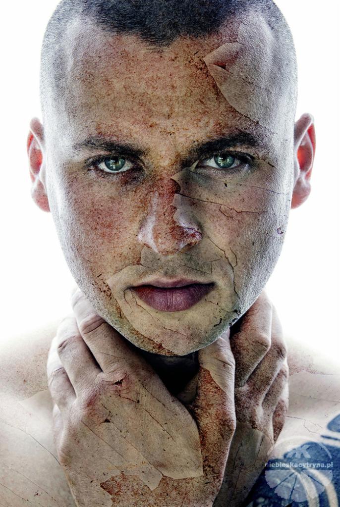 Portret mężczyzny z nałożoną teksturą pękniętej ziemi i elementami kolażu, podkreślony intensywnym oświetleniem i zielonymi oczami.