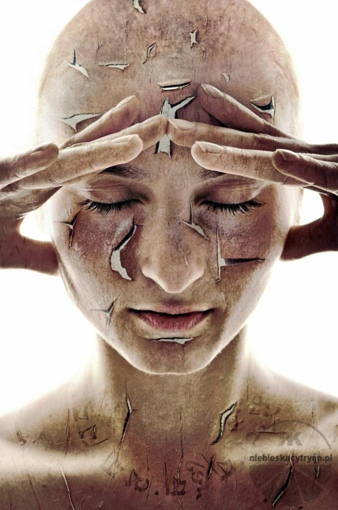 Portret kobiety z zamkniętymi oczami, z efektem pękającej skóry i nałożonymi dłońmi na czoło, ukazujący koncept kruchości lub transformacji.