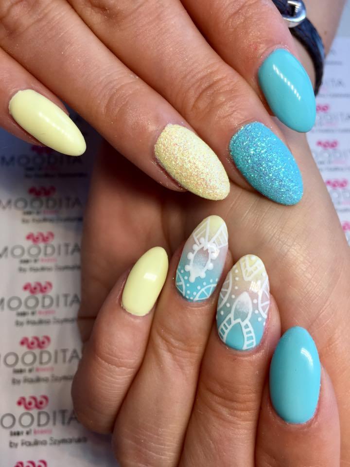 Pastelowe paznokcie w odcieniach żółci i błękitu: gładki lakier, brokat i wzory geometryczne na tle podkładki z logo.