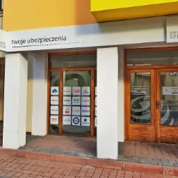 Fasada biura ubezpieczeniowego Spectrum z widocznymi logotypami różnych towarzystw ubezpieczeniowych na szybie i szyldzie informacyjnym.