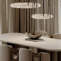 Beżowa jadalnia: stół z kamiennym blatem, krzesła z drewnianymi elementami i marmurowe lampy wiszące. Na stole książka i dekoracyjna misa. Stonowana kolorystyka.