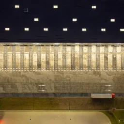 Widok z drona na plac rozładunkowy magazynu z zaparkowaną ciężarówką, widoczne doki rozładunkowe, oznakowanie poziome i oświetlenie nocne.