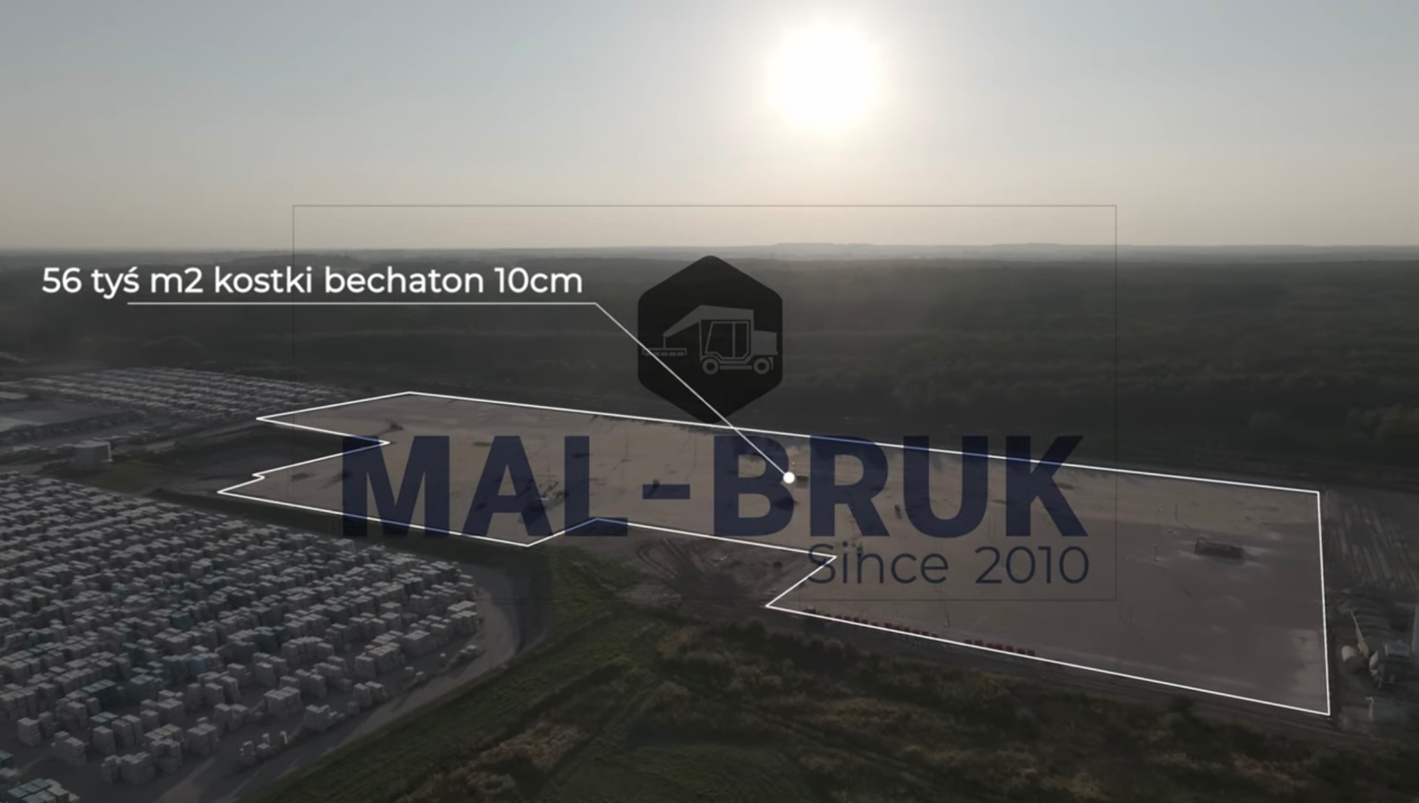 Widok z drona na plac budowy z kostką behaton 10cm, zarys terenu i logo firmy MAL-BRUK 'Since 2010', w tle las.