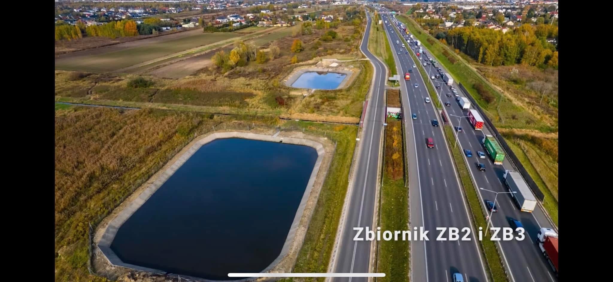Widok z drona na zbiorniki retencyjne ZB2 i ZB3 wzdłuż autostrady, z widocznym ruchem pojazdów i otaczającym krajobrazem.