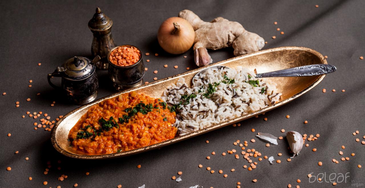 Danie kuchni indyjskiej: dal z soczewicy z ryżem basmati i dzikim ryżem, podane na złotej tacy z dekoracją z cebuli, imbiru i czosnku, uzupełnione o metalowe naczynia na przyprawy i rozsypane...
