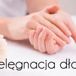 Dłonie kobiety z naturalnym manicure, sfotografowane na białym ręczniku obok jasnej gerbery. Tekst 'Pielęgnacja dłoni' na pierwszym planie.