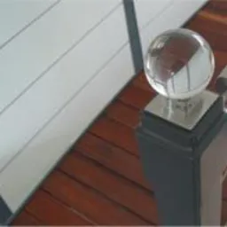 Nowoczesny balkon z szklaną balustradą i narożnym oknem, oraz drewniane schody z balustradą z elementami szklanymi i ozdobną szklaną kulą na słupku.