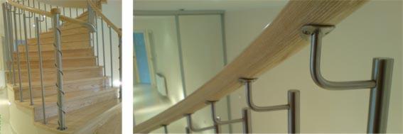 Drewniane schody z metalowymi balustradami i poręczą, widoczne detale mocowania poręczy do ściany, jasne wnętrze.