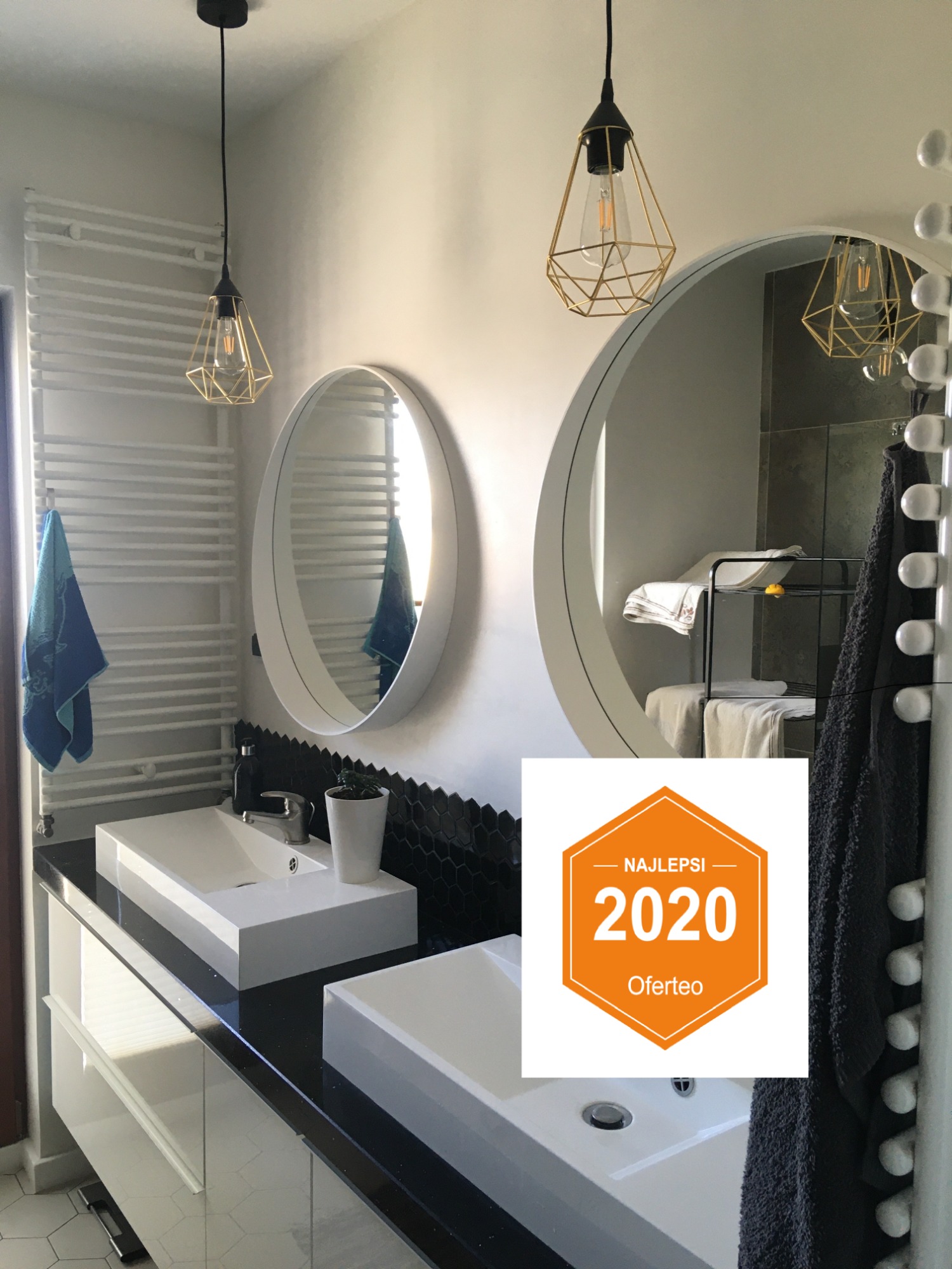 Nowoczesna łazienka z dwiema prostokątnymi umywalkami nablatowymi na czarnym blacie, okrągłe lustra, geometryczne lampy wiszące, grzejnik drabinkowy i heksagonalna mozaika na ścianie, częściowo...