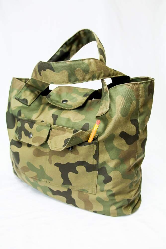 Torba shopper z tkaniny w kamuflażu wojskowym, z trzema kieszeniami z przodu, z których jednej wystaje ołówek.