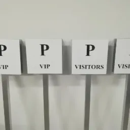 Cztery tabliczki informacyjne na metalowych stojakach z napisem 'P VIP' i 'P VISITORS' na białym tle.