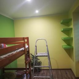 Usługi ogólnobudowlane - Pokój dziecięcy z łóżkiem piętrowym, ścianami w dwóch odcieniach zieleni i żółci oraz drabina malarska stojąca na drewnianej podłodze.