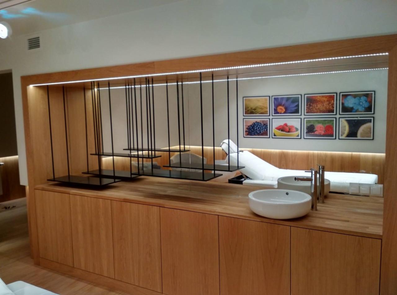 Nowoczesna zabudowa drewniana z wiszącymi półkami na czarnych linkach, podświetleniem LED i umywalkami nablatowymi, uzupełniona o dekoracyjne obrazy na ścianie.