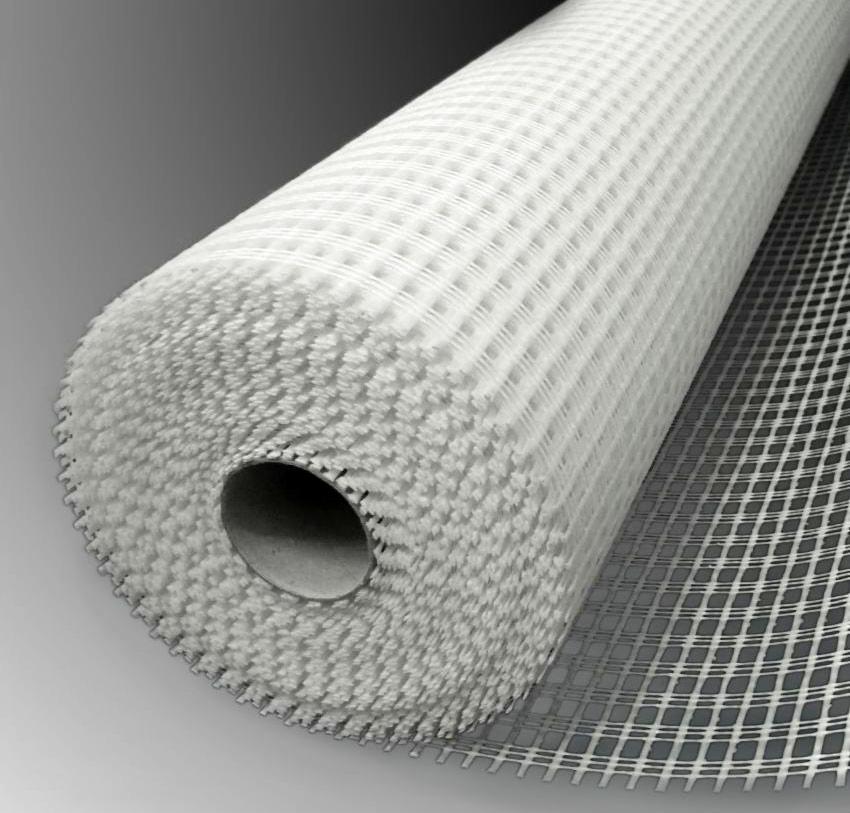Rolka białej siatki z włókna szklanego, widoczna struktura oczek i tekstura materiału z bliska.