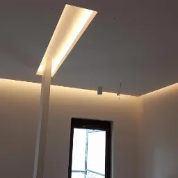 Nowoczesne oświetlenie sufitowe z wnękami i listwami LED, widok na białe ściany i stolarkę okienną w minimalistycznym wnętrzu.