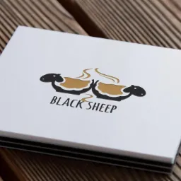 Wizytówka z logo firmy Black Sheep przedstawiającym dwie czarne owce z parującą wełną w kolorze złota, leżąca na drewnianym blacie.