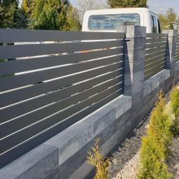 Ogrodzenie palisadowe zamontowane na ogrodzeniu betonowym w oparciu o sztachety aluminiowe malowane proszkowo. 