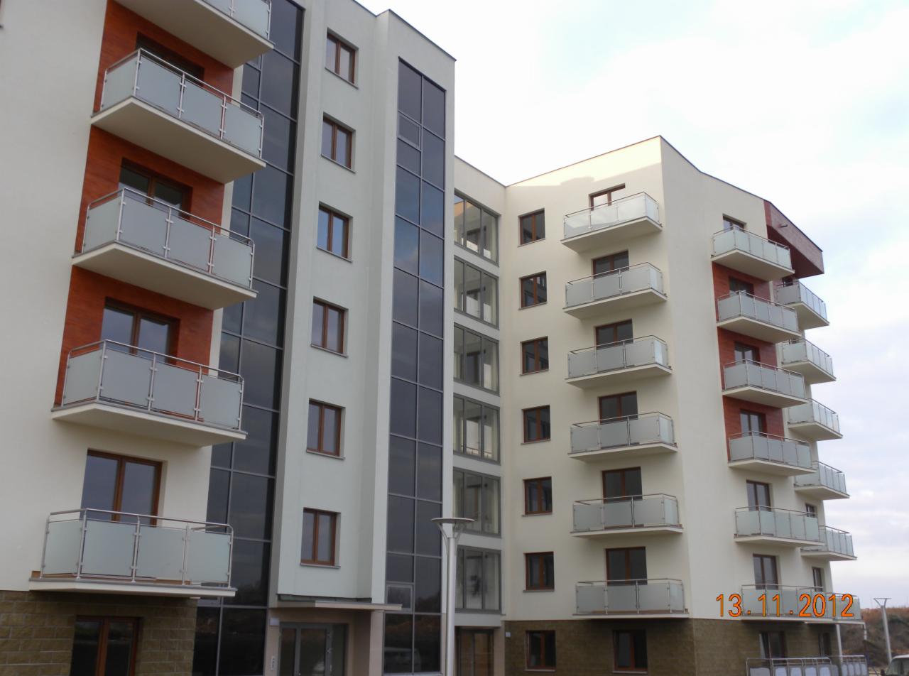 Nowoczesny budynek wielorodzinny z balkonami zabezpieczonymi balustradami ze szkła matowego i metalu, widok z dołu na elewację w stonowanej kolorystyce z elementami cegły, data 13.11.2012 w prawym...