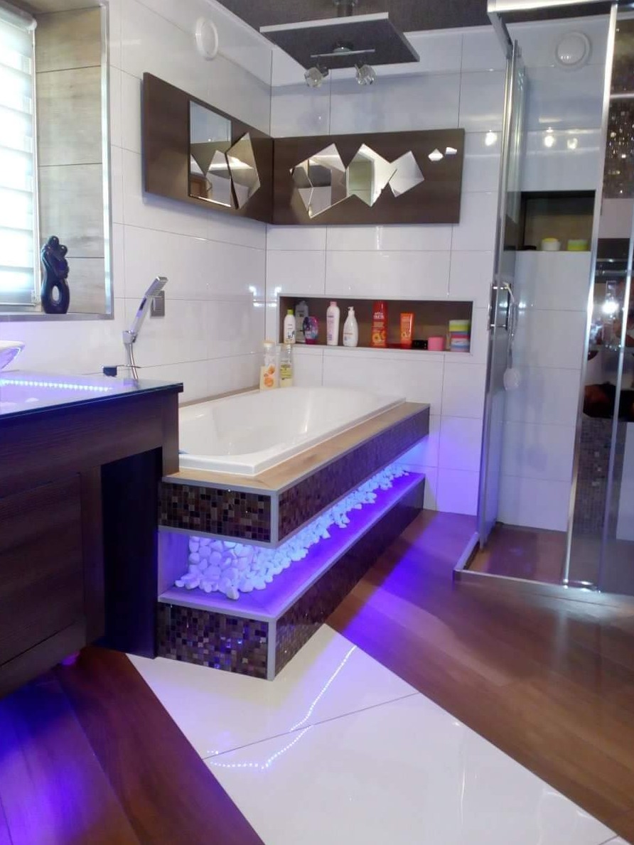 Nowoczesna łazienka w Starych Bogaczowicach z wanną na podwyższeniu wykończonym mozaiką, podświetlonymi półkami z dekoracyjnymi kamieniami i oryginalnymi lustrami na ścianie.