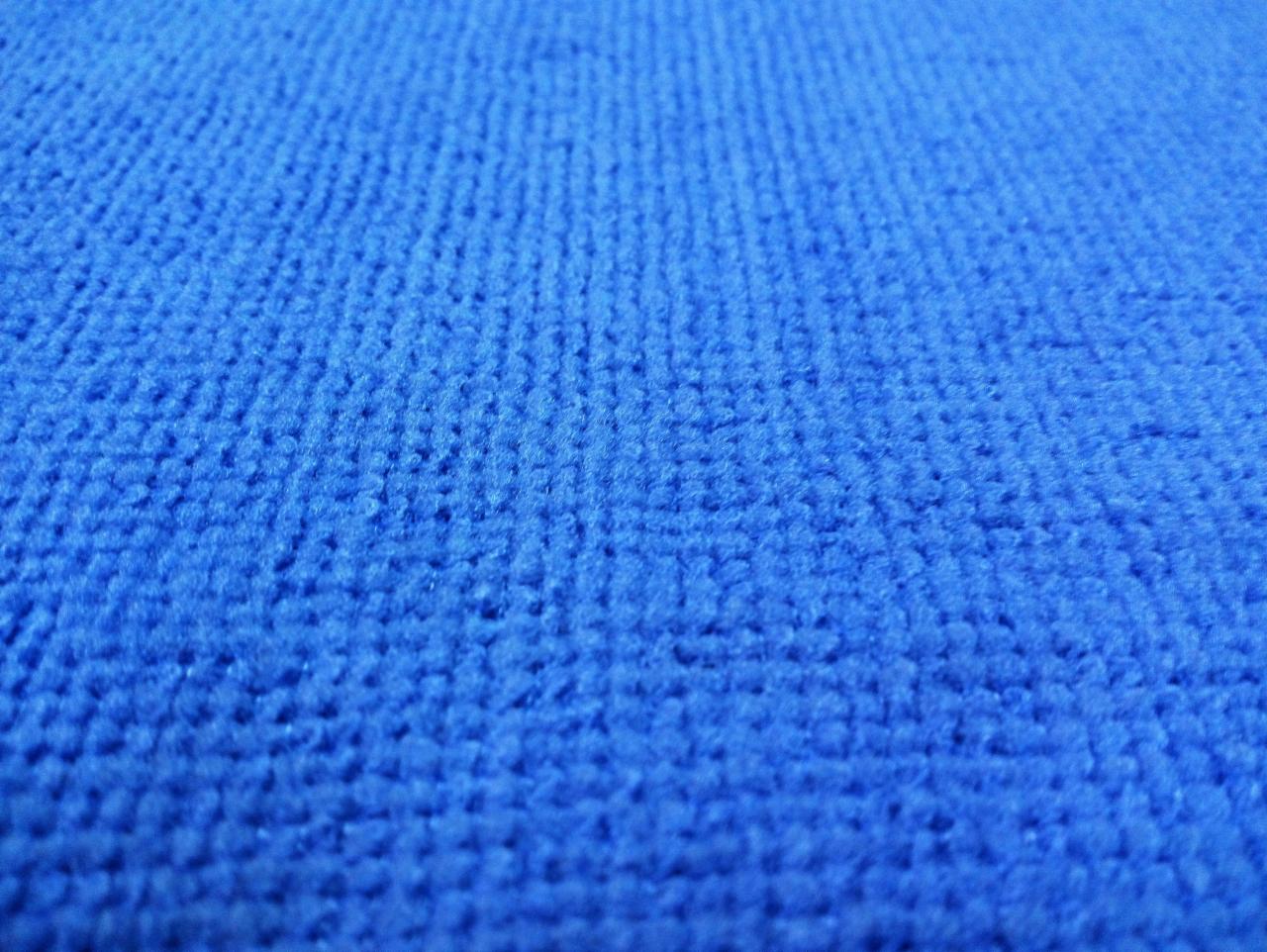 Niebieska tkanina o wyraźnej, pętelkowej strukturze, sfotografowana pod kątem z bliska, ukazująca detale splotu.