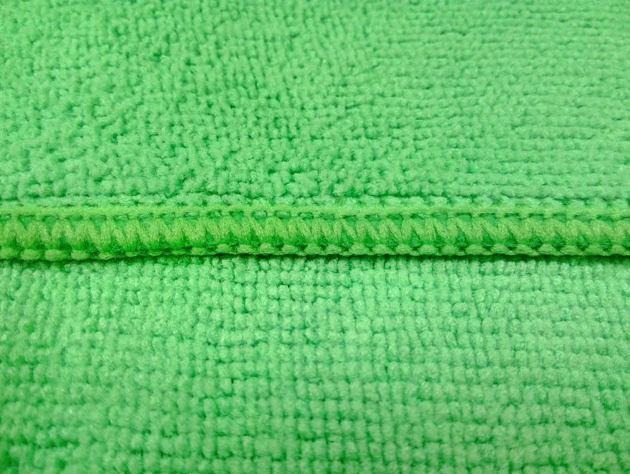 Jasnozielona tkanina frotte z wyraźnym szwem na środku, widoczna struktura materiału.